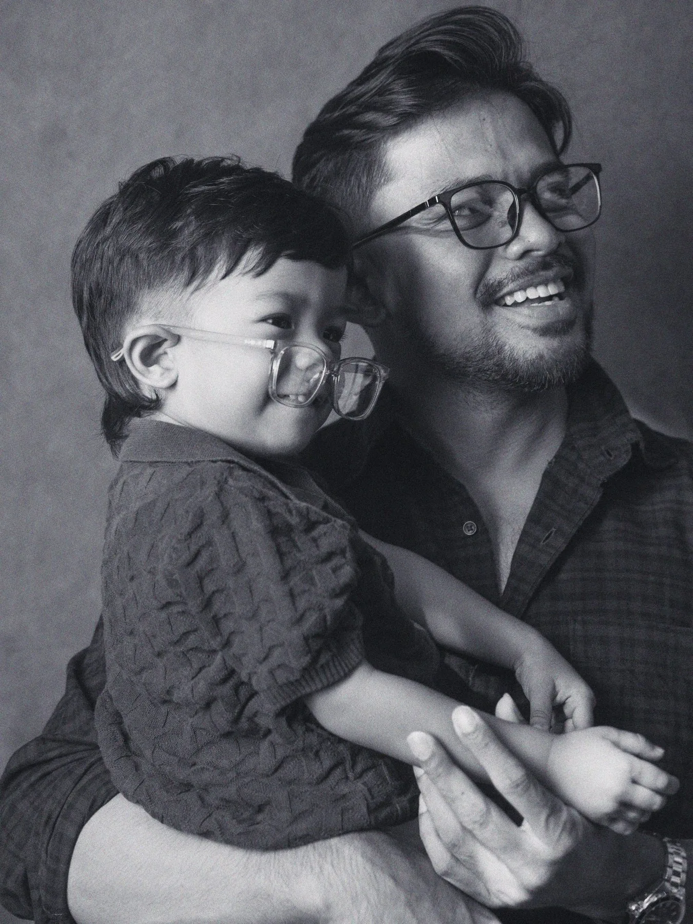 A father and son trying on kids glasses together